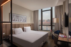 A hotel room with a large bed, a desk with a chair, a TV, and a window with curtains. - NH Milano Corso Buenos Aires  (Milan)