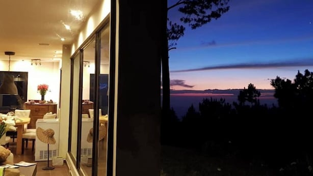 Et moderne interiør med en stor glasdør, der fører ud til en balkon med udsigt over et smukt landskab.