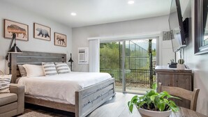 Une chambre à coucher comprenant un lit, une table de chevet, une lampe et une vue sur l’extérieur grâce à une porte-fenêtre coulissante.