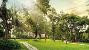 A well-maintained park with a paved walkway, lush greenery, and trees providing shade. - Rosetta-Sakleshpur (Alur)