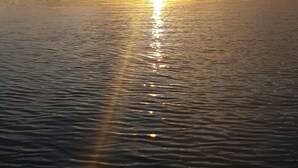 Ein Sonnenuntergang über ruhigem Meer mit klarem Horizont.