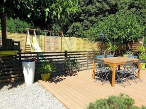 Relax on the outdoor patio with a wooden table and four chairs, surrounded by lush potted plants and a comfortable bench.