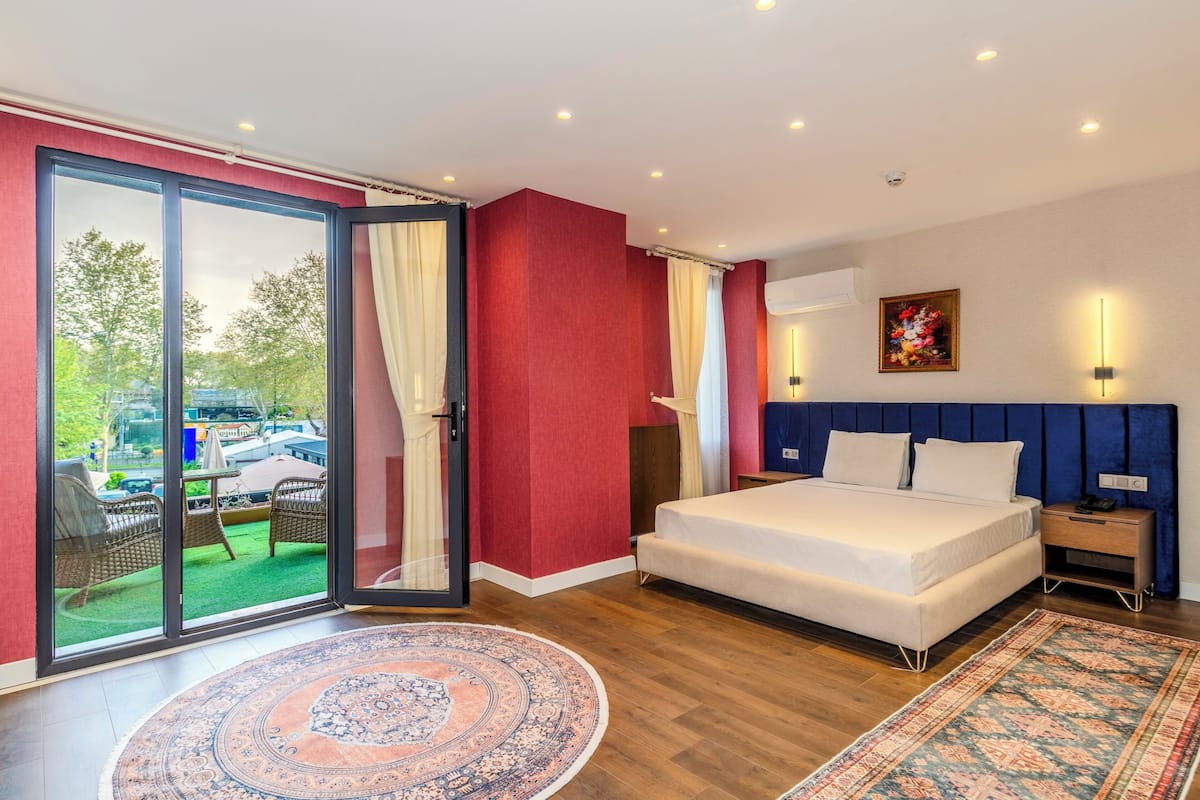 A bedroom with a large bed, a sliding glass door to a balcony, and a view of the outside.