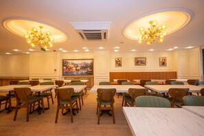 A restaurant with multiple tables and chairs, a large painting on the wall, and two chandeliers. - Porta Romanos Hotel (Istanbul)