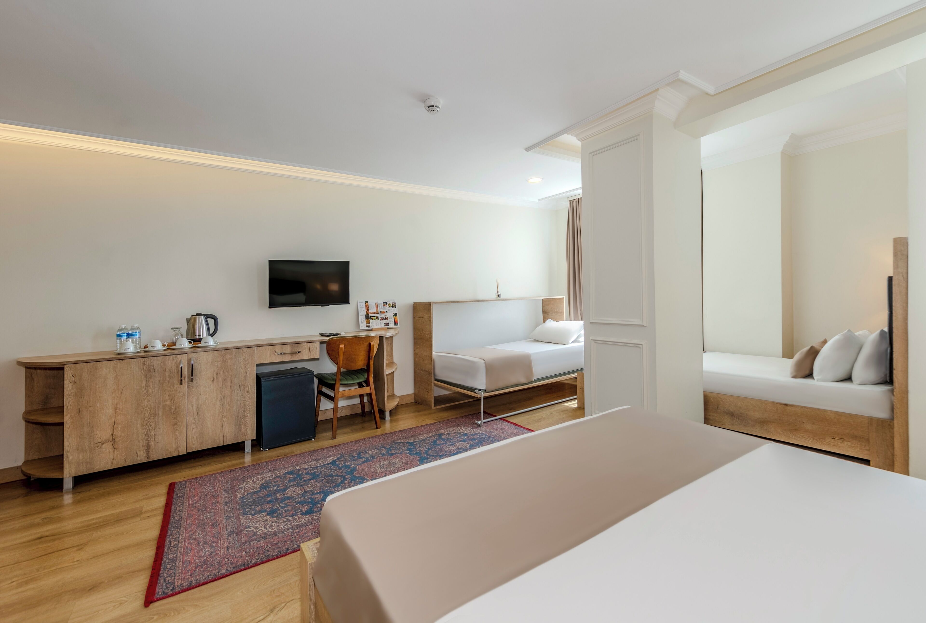 A modern hotel room with a bed, a desk, a chair, a TV, and a sofa.