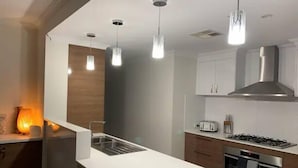 Uma cozinha moderna com luminárias pendentes, fogão a gás e forno embutido.