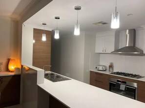 Una cucina moderna con lampade a sospensione, un piano cottura a gas e forno integrato.