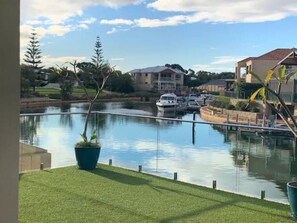 A marina with boats, a grassy area, and buildings in the background.