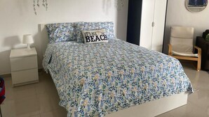A bedroom with a bed, a nightstand, a wardrobe, and a chair. - Cómodo y Confortable Estudio Frente al mar (Playa Juan Dolio)
