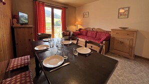 Un comedor con una mesa dispuesta para cuatro personas, un sofá y un aparador de madera.