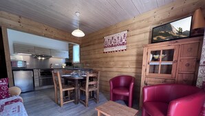 Interior acollidor d'una cabana amb zona de dinar de fusta, cuina amb electrodomèstics moderns i un sofà de pell vermella.