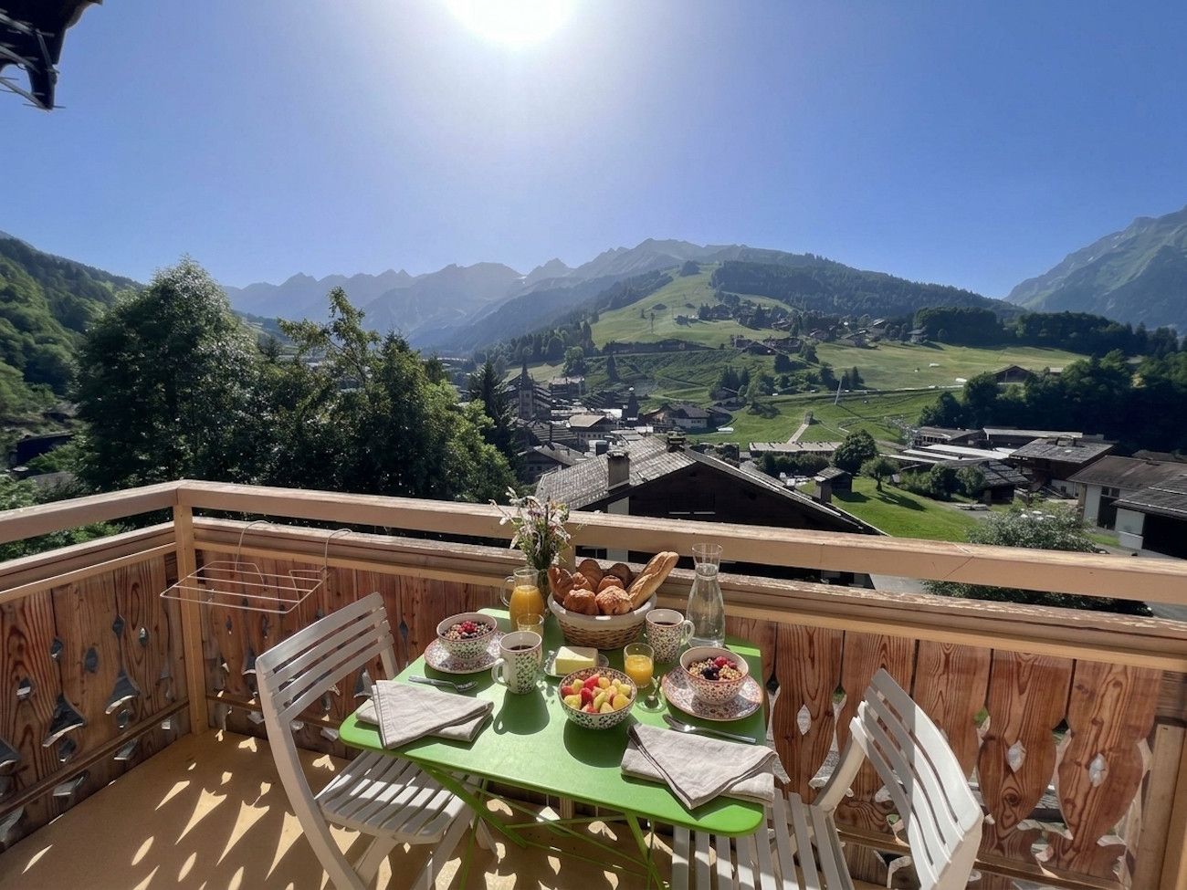 A balcony with a table set for breakfast overlooking a mountainous landscape.