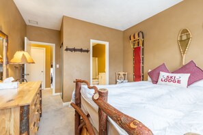 Een slaapkamer met een houten bedframe, een nachtkastje, een lamp en een kussen in skistijl.