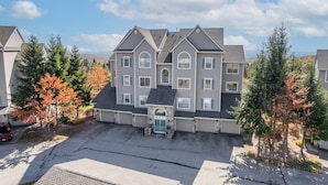 A multi-story residential building with a central entrance, surrounded by trees with autumn foliage. - Prime Resort Location, Modern Ski/Out w/ Balcony (Champion)