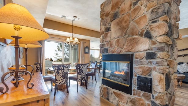 A cozy interior with a stone fireplace, wooden furniture, and a dining area. - Prime Resort Location, Modern Ski/Out w/ Balcony (Champion)