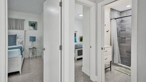 A modern bedroom with a bed, bedside table, and lamp. There is a bathroom with a shower and a toilet. - Luxury & Comfy Pool Getaway ~ Mins to Beaches & DT (Fort Lauderdale)