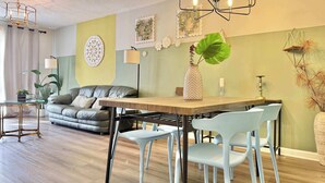 Una sala de estar moderna con un sofá, mesa de comedor, sillas y una araña.
