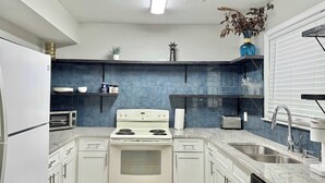 Una cocina moderna con armarios blancos, una estufa blanca, un microondas y un lavavajillas.