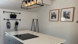 A modern kitchen with a central island, black cabinets, and a hanging light fixture. - Beautiful Cuppin Street Two Bed Apartment (Chester)