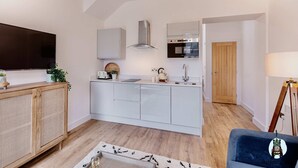 Une cuisine moderne avec des meubles blancs, un four encastré et une porte en bois.