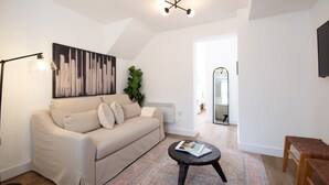 A living room with a sofa, a coffee table, a floor lamp, a painting, and a plant.