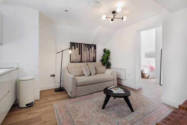 A modern living room with a sofa, a coffee table, a floor lamp, and a painting on the wall.