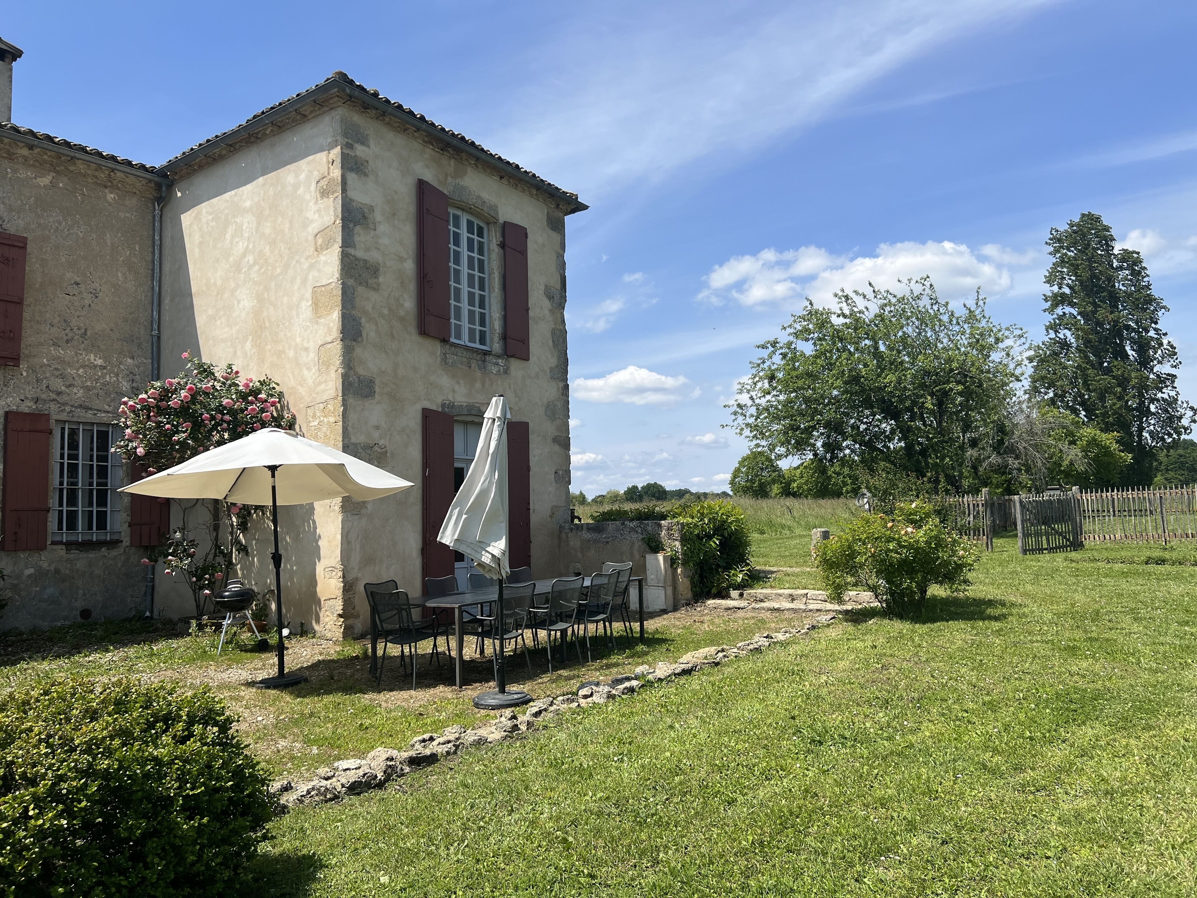 A rustic stone building with a patio area featuring outdoor seating and a white umbrella.