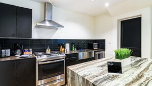 Et moderne køkken med rustfrie stålapparater, en sort bagplade og en marmorbordplade.