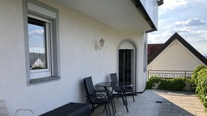 Eine Terrasse mit Tisch und Stühlen, einem Heizkörper und einem Fenster mit Blick.
