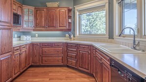 Una cocina con armarios de madera, microondas integrado y ventana con vistas a árboles.