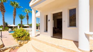 A resort with a pool, palm trees, and a covered outdoor area with steps leading to a building. - Queens Paradise 1 - Three Bedroom Villa, Sleeps 6 (Peyia)