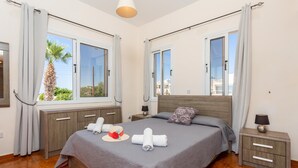 A hotel room with a large bed, wooden headboard, and two bedside tables. - Queens Paradise 1 - Three Bedroom Villa, Sleeps 6 (Peyia)