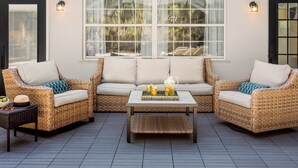 A cozy outdoor seating area with wicker furniture and a central coffee table.