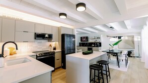 A modern kitchen with white cabinetry, a central island, and a dining area with a table and chairs.