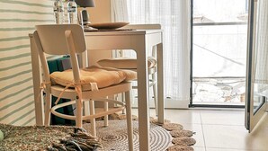 Une pièce moderne avec une table et des chaises, une lampe, et une vue à travers une porte vitrée.