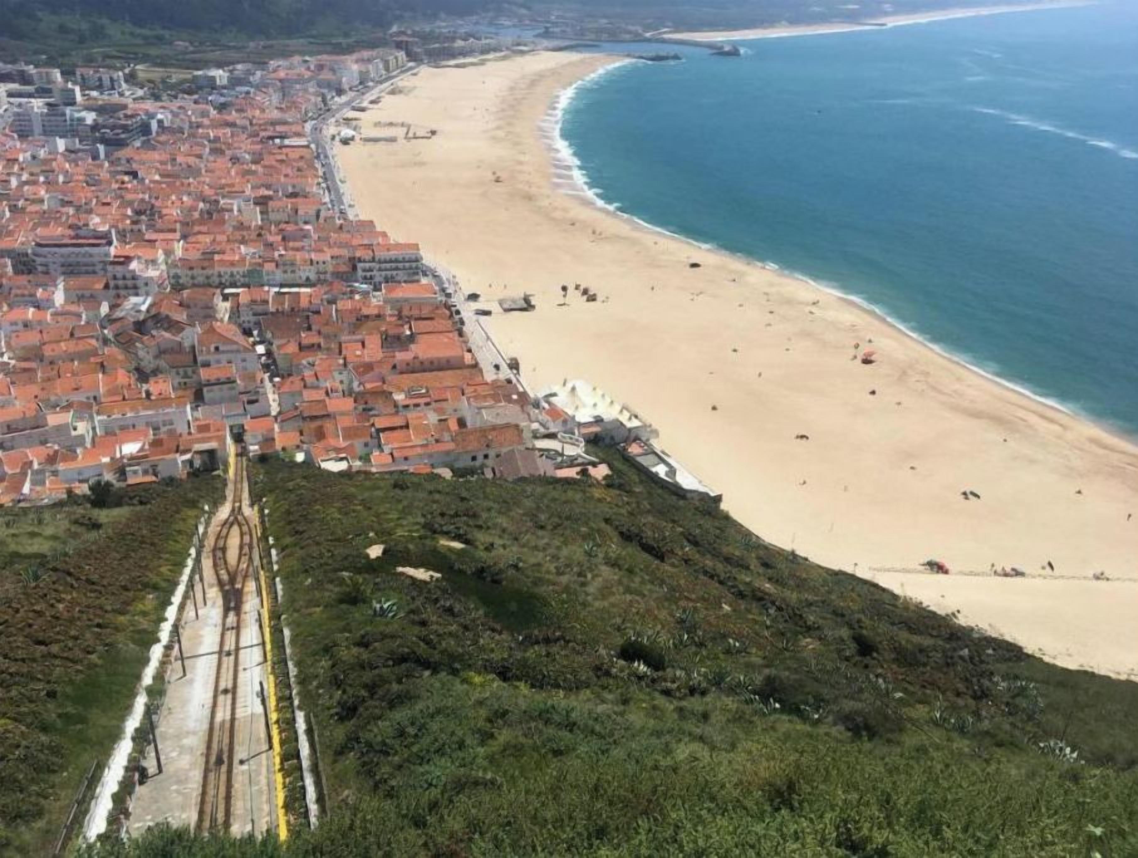A coastal cityscape with a beach, railway tracks, and residential buildings.