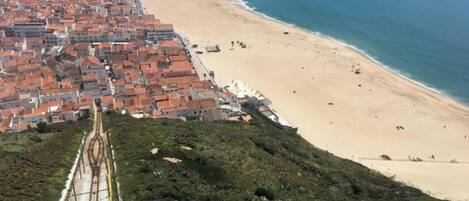 A coastal cityscape with a beach, railway tracks, and residential buildings.