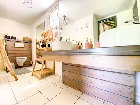 A bathroom with a wooden vanity, a large mirror, and a toilet.