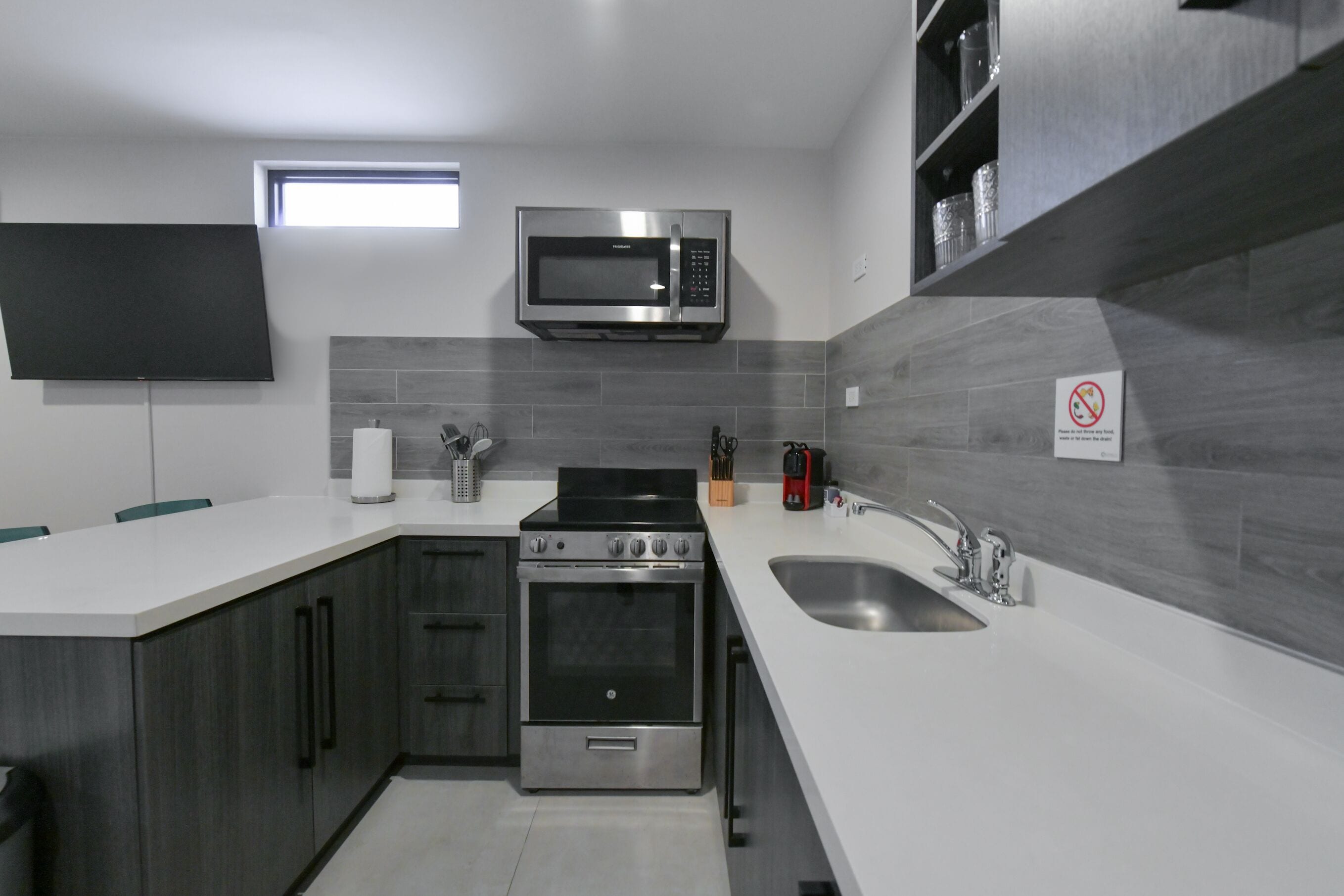 A modern kitchen with a built-in microwave, oven, and sink.