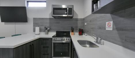 A modern kitchen with a built-in microwave, oven, and sink.