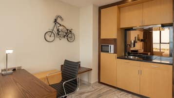 Una cocina moderna con armarios de madera, un microondas integrado y una obra de arte con motivo de bicicleta en la pared.