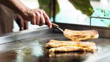 Una persona cortando un sándwich a la parrilla sobre una plancha.