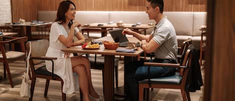 A couple dining at a restaurant with wooden furniture and a modern interior.