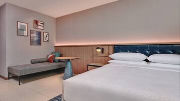 Habitación de hotel con cama, sofá, una mesita y decoración en la pared.