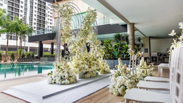 Un espace extérieur avec piscine, agrémenté de compositions florales blanches et de sièges.