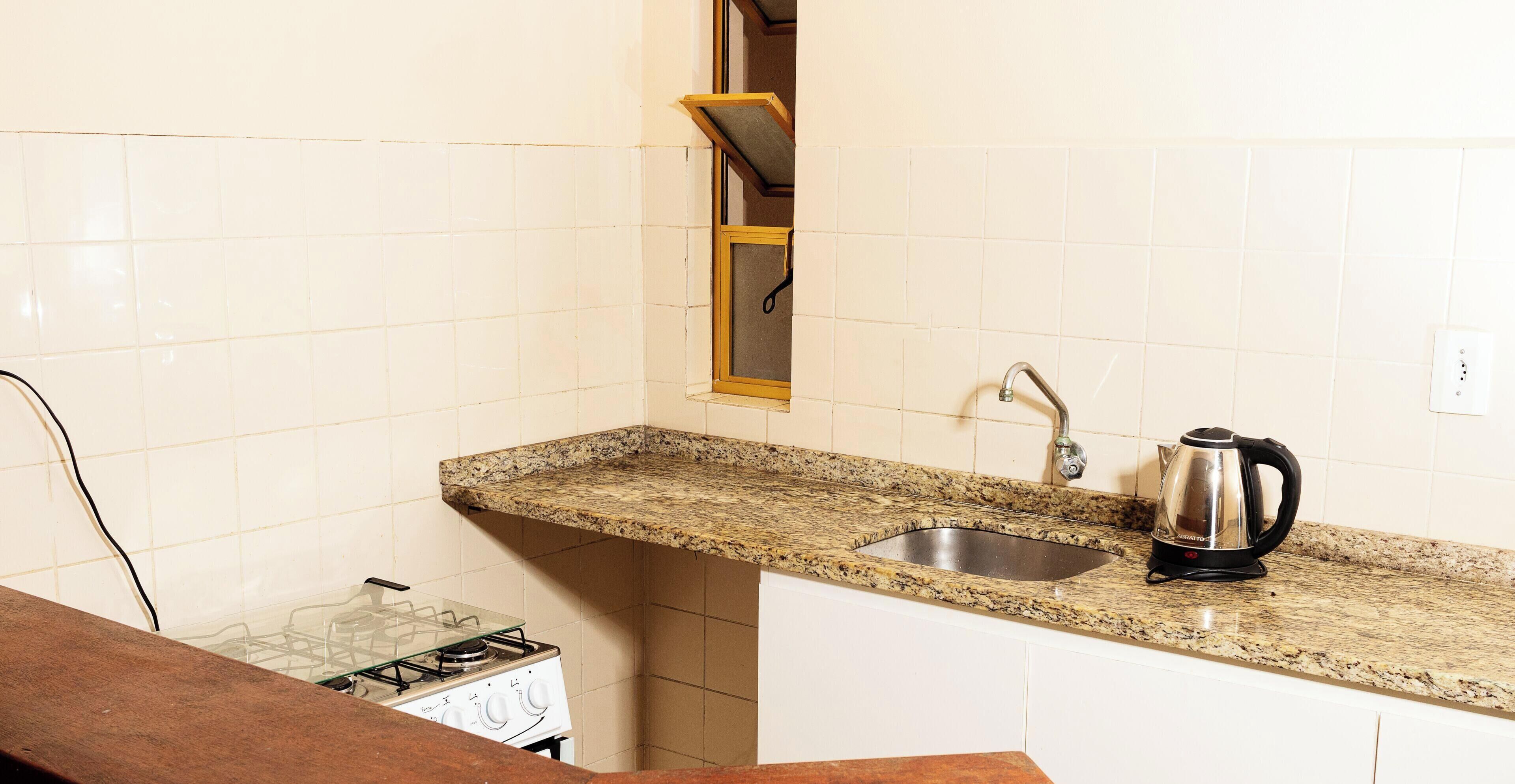 Una cocina con encimera de granito, pileta de acero inoxidable y hervidor.