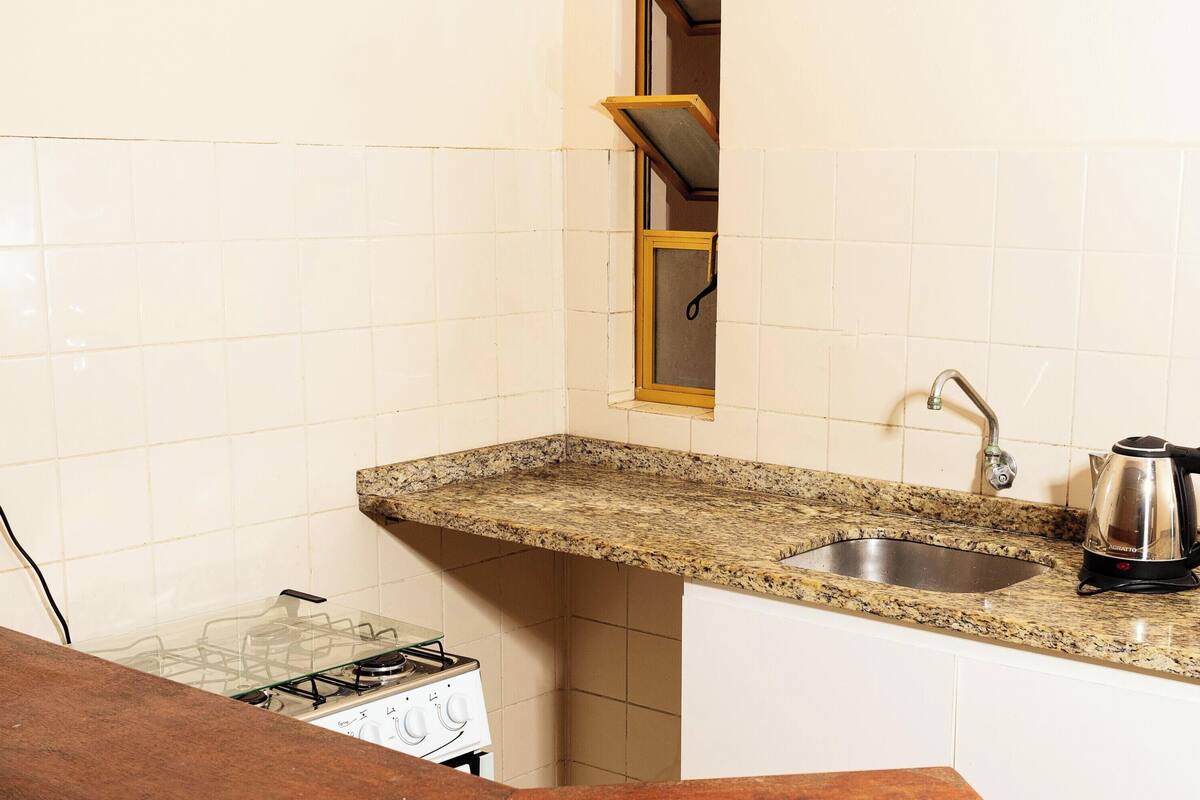 Una cocina con encimera de granito, pileta de acero inoxidable y hervidor.