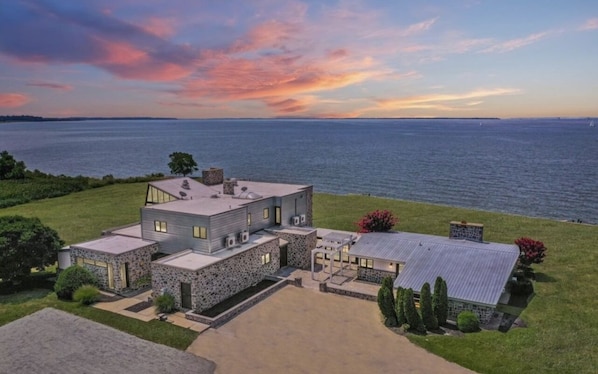 A modern house with a stone facade, a large garage, and a spacious driveway.