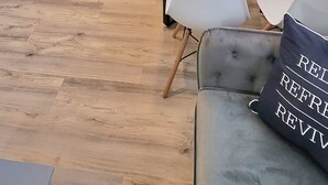Une cuisine moderne avec des meubles blancs, une horloge noire et un coin repas comprenant une table et des chaises.
