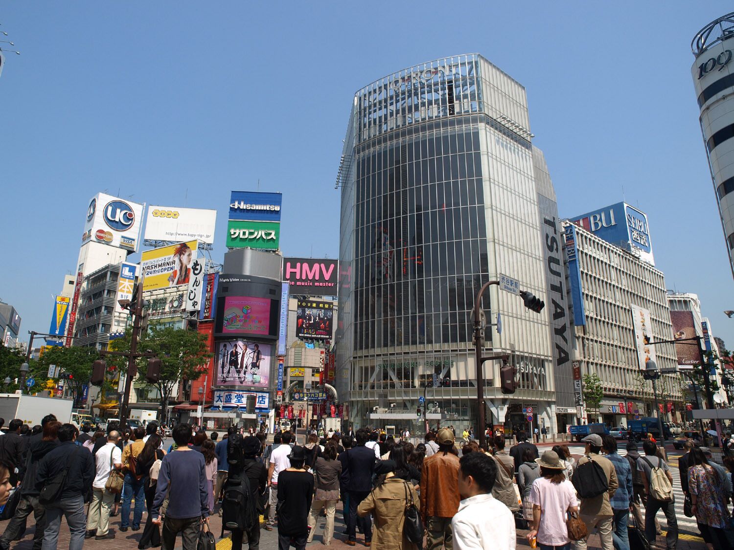 A busy urban street with modern buildings and various commercial signs.